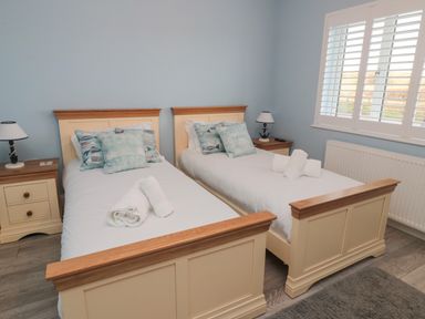A bedroom with two single beds white bedding and rolled towels on each bed at Bamburgh Dunes Bamburgh near Seahouses