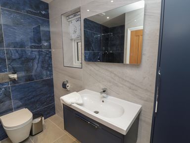 A bathroom with a sink and mirror next to a toilet and a small window at Bamburgh Dunes Bamburgh near Seahouses