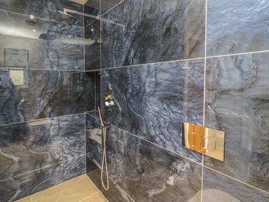 A shower area with dark blue marble tiles and chrome fixtures at Bamburgh Dunes Bamburgh near Seahouses