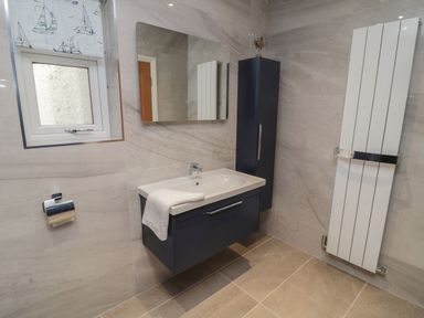 A bathroom with a floating sink cabinet mirror radiator window with boat patterned blind at Bamburgh Dunes Bamburgh near Seahouses