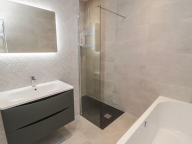 A bathroom with a sink and cabinet a mirror a glass shower enclosure and a bathtub at Bamburgh Dunes Bamburgh near Seahouses