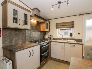 A kitchen with gas stove oven sink window and cabinets at Hudson's Hideaway in South Lakeland Leisure Village