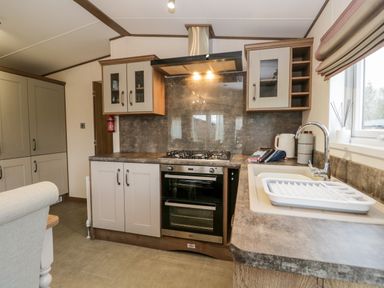 A kitchen with a stove oven a sink with a drying rack cabinets and a window at Hudson's Hideaway in South Lakeland Leisure Village