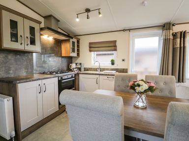A kitchen and dining area with a gas stove oven sink dining table with chairs and flowers at Hudson's Hideaway South Lakeland Leisure Village