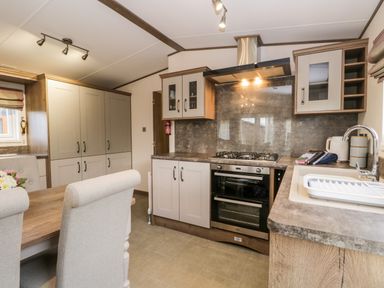 A kitchen with a stove oven sink cabinets and a dining table with chairs at Hudson's Hideaway in South Lakeland Leisure Village