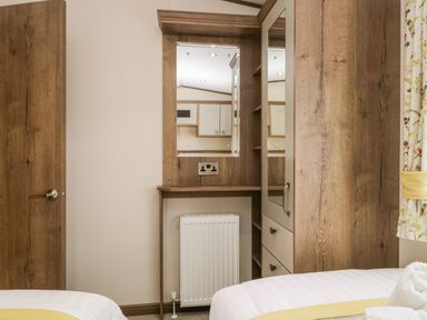 A bedroom corner with a wooden door mirror wardrobe radiator and part of a bed at Hudson's Hideaway in South Lakeland Leisure Village