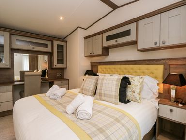 A bedroom with a bed with pillows and rolled towels a chair and a vanity unit at Hudson's Hideaway in South Lakeland Leisure Village