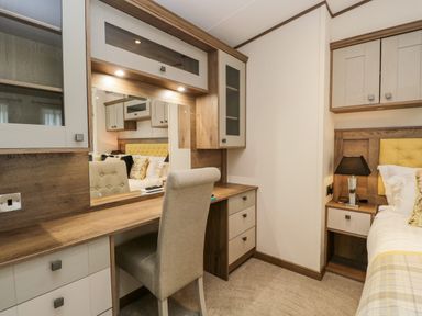 A bedroom with a dressing table mirror chair bedside table lamp and bed at Hudson's Hideaway South Lakeland Leisure Village