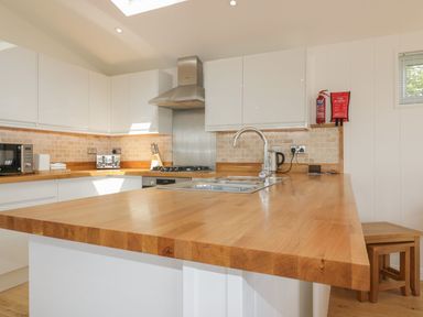 A kitchen with wooden countertops white cabinets and appliances at 2 Faraway Fields in Dobwalls