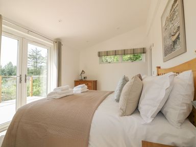 A bedroom with a double bed, pillows, folded towels, wooden dresser, and glass doors at 2 Faraway Fields Dobwalls