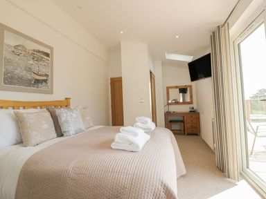 A bedroom with a bed a desk a wall-mounted TV and a sliding glass door at 2 Faraway Fields in Dobwalls
