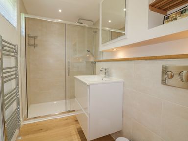 A bathroom with a walk-in shower a white sink unit a chrome towel rack and a mirror at 2 Faraway Fields in Dobwalls