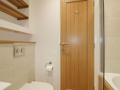 A bathroom with a wooden door a toilet with a toilet paper holder and a bathtub at 2 Faraway Fields in Dobwalls
