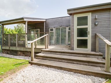 A wooden deck with steps and glass railing outside a house at 6 Southern Place in Dobwalls