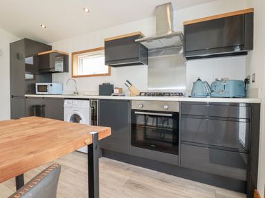 A kitchen with grey cabinets microwave washing machine oven and blue toaster kettle at 6 Southern Place in Dobwalls