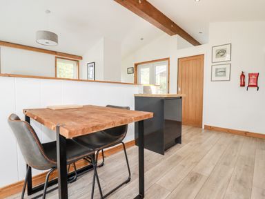 A dining area with a wooden table and black chairs next to a kitchen island with wooden countertop at 6 Southern Place in Dobwalls
