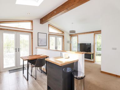 A dining area with table and chairs next to glass doors and a living room with a TV and lamp at 6 Southern Place in Dobwalls