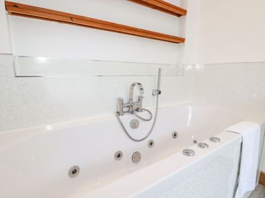 A white bathroom with a built in bathtub with jets and a mounted shower head at 6 Southern Place Dobwalls
