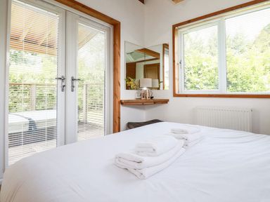 A bedroom with a bed and folded towels with glass doors and a window at 6 Southern Place in Dobwalls