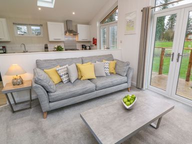 A living room with a sofa with cushions a coffee table with a bowl of green apples and a side table lamp at 4 Faraway Fields Dobwalls