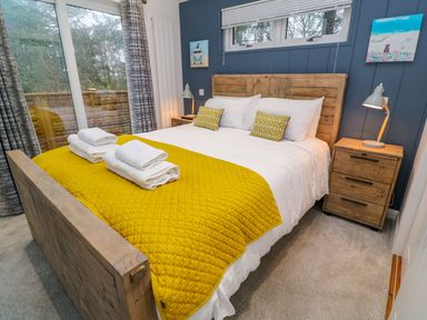 A bedroom with a wooden bed frame white bedding yellow blankets and pillows beside wooden nightstands with lamps at 4 Faraway Fields in Dobwalls