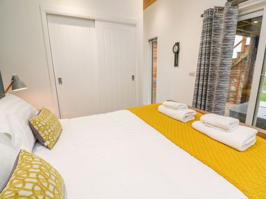 A bedroom with a bed that has white sheets and yellow pillows and blanket with folded towels on top at 4 Faraway Fields in Dobwalls