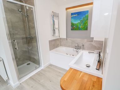 A bathroom with a shower, bathtub, sink, and a painting above the bathtub at 4 Faraway Fields in Dobwalls