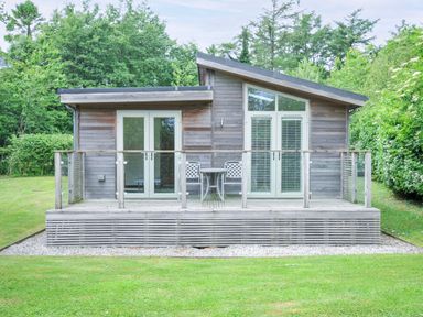 A cottage with a deck and chairs at 5 Faraway Fields Dobwalls