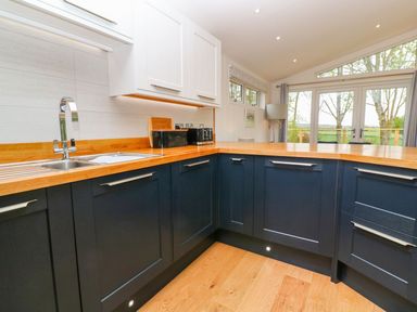 A kitchen with dark lower cabinets white upper cabinets wooden countertops and a window overlooking trees at 21 Meadow Retreat in Dobwalls