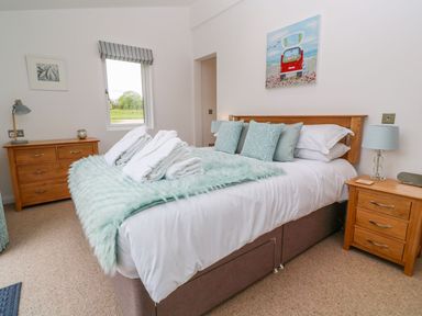 A bedroom with a double bed with teal pillows and a teal throw at 21 Meadow Retreat in Dobwalls