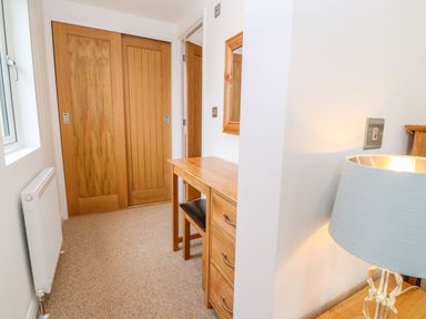 A hallway with wooden sliding doors a wooden desk with a chair a mirror and a lamp at 21 Meadow Retreat in Dobwalls