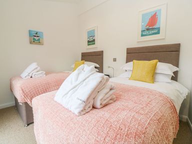 A bedroom with two single beds yellow pillows and folded white robes on the beds at 21 Meadow Retreat in Dobwalls