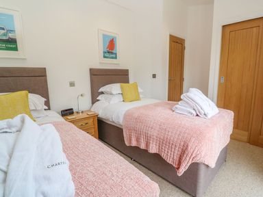 A bedroom with two single beds with pink blankets and yellow pillows at 21 Meadow Retreat in Dobwalls