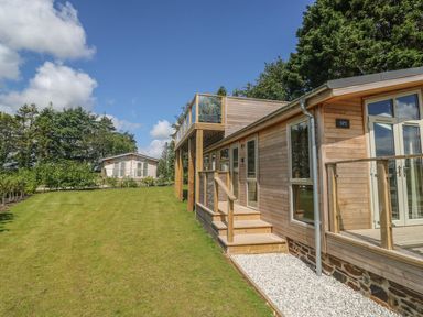 A wooden house with glass doors and windows on a lawn with trees in the background at 2 Southern Place in Dobwalls