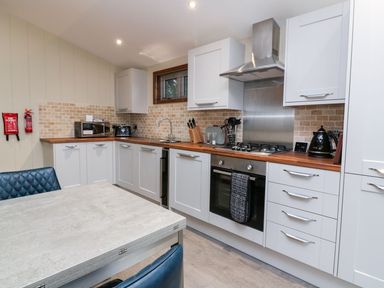 A kitchen with white cabinets wooden countertops stainless steel oven and hood and a dining table with blue chairs at 2 Southern Place in Dobwalls