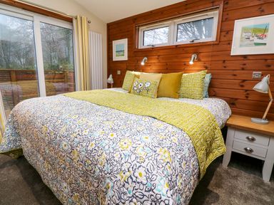 A bedroom with a bed with floral and yellow bedding and a wooden wall with two framed pictures at 2 Southern Place in Dobwalls