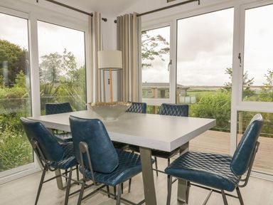 A dining area with a rectangular table and six blue chairs near large windows at 7 Faraway Fields in Dobwalls