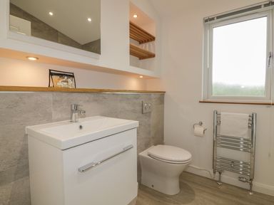 A bathroom with a white sink cabinet toilet a window and a heated towel rail at 7 Faraway Fields in Dobwalls