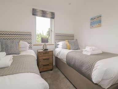 A bedroom with two single beds with patterned headboards a wooden nightstand with a lamp and a window between the beds at 7 Faraway Fields in Dobwalls