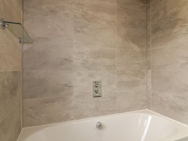 A bathroom with a white bathtub and beige tiled walls at 7 Faraway Fields in Dobwalls