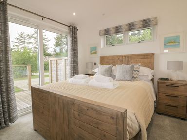A bedroom with a wooden bed and nightstands with lamps beside sliding glass doors at 7 Faraway Fields in Dobwalls