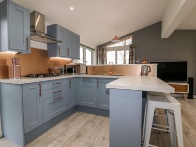 A kitchen with blue cabinets and copper accents including a faucet knife holder and kettle at 19 Meadow Retreat in Dobwalls