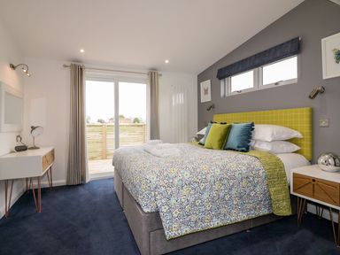 A bedroom with a bed wardrobe side tables and sliding glass door at 19 Meadow Retreat in Dobwalls