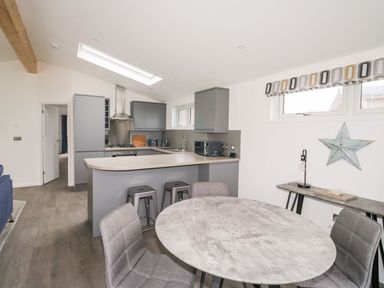 A kitchen with grey cabinets and counters a round dining table with chairs and a small table against the wall with a star decoration at 1 Southern Place in Dobwalls