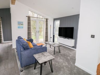 A living room with a blue sofa a coffee table a side table and a wall-mounted TV at 1 Southern Place in Dobwalls