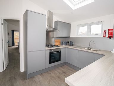 A kitchen with grey cabinets oven stove sink and window at 1 Southern Place in Dobwalls