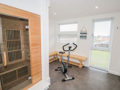 A room with a stationary exercise bike a wooden corner bench and a wooden sauna at 1 Southern Place in Dobwalls