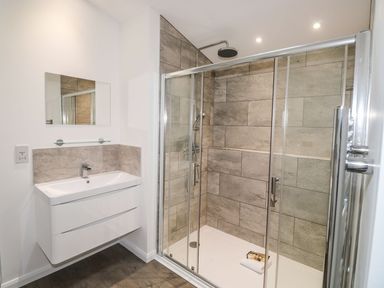 A bathroom with a sink, mirror, and a glass enclosed shower with tiled walls at 1 Southern Place in Dobwalls