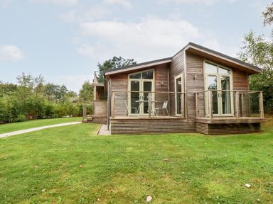 A wooden house with glass doors and a small patio with chairs and a table at 1 Southern Place in Dobwalls