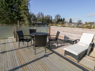 An outdoor wooden deck with a round table and four chairs and a lounge chair at 1 Southern Place in Dobwalls
